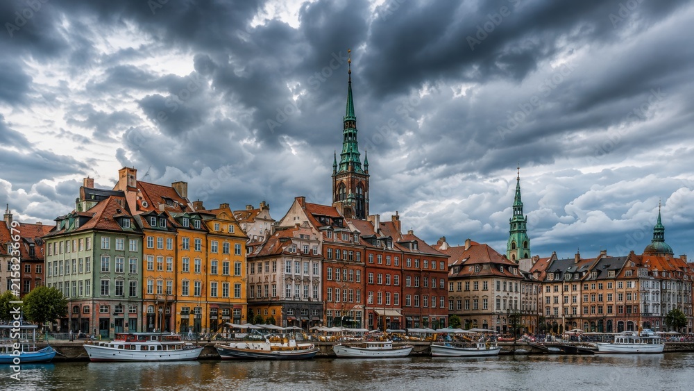 Fototapeta premium Panoramic medieval coastal town with historic towers under stormy skies at dusk