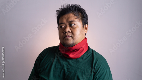 Quadro su tela A young Southeast Asian male looks away with a subtle expression of annoyance or suspicion against a plain light grey background