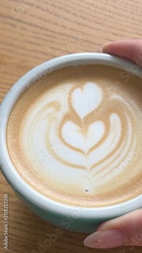 Close up latte art coffee with heart and flower foam in turquoise cup on cafe table