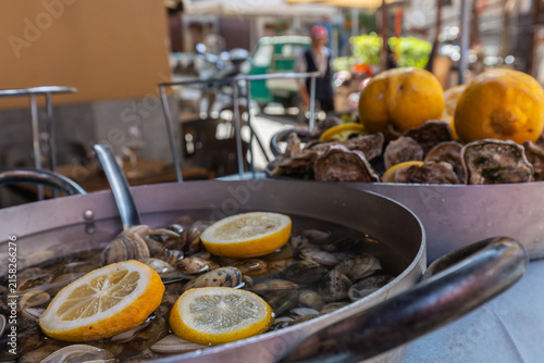 Pfanne mit Venusmuscheln und Zitronen in Palermo. Im Hintergrund eine Pfanne mit Austern und Zitronen.