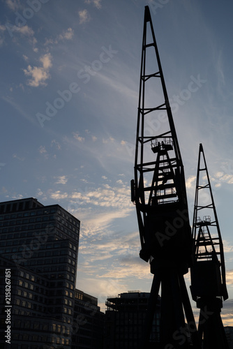 Cuadro en lienzo Silhouetted Industrial Cranes Against a Blue Evening Sky in Urban Setting