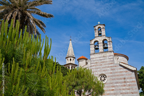 Fotografie Old stone church in Budva, Montenegro, with Mediterranean palm trees