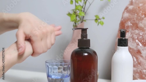 Woman performing a relaxing hand and wrist self massaging as part of a wellness and selfcare routine at home. Female applying cream from tube to care moisturizing her palms skin