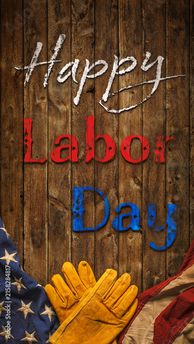 Patriotic Happy Labor Day text with worn work gloves and the USA flag on wooden background. Symbolic of the American labor movement and pride in America's blue collar workers. Celebrate US Labor Day.