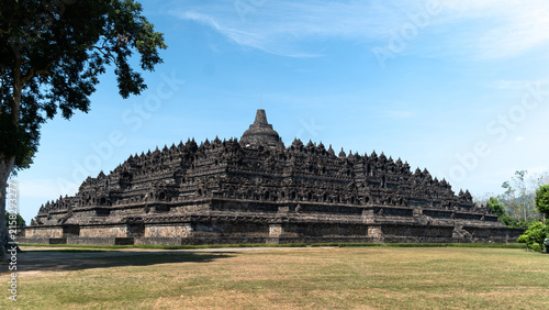 The ancient Borobudur temple, a magnificent Buddhist monument, stands majestically under a clear blue sky, its intricate stone carvings telling tales of history and spirituality.