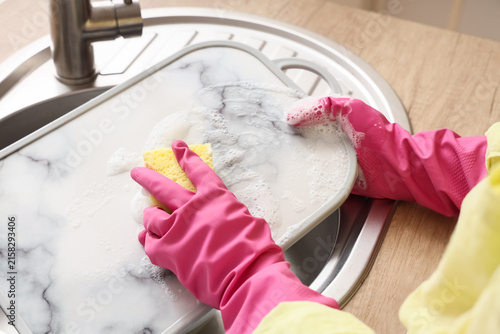 Canvastavla Person in pink rubber gloves washing a marble-patterned cutting board with a yel