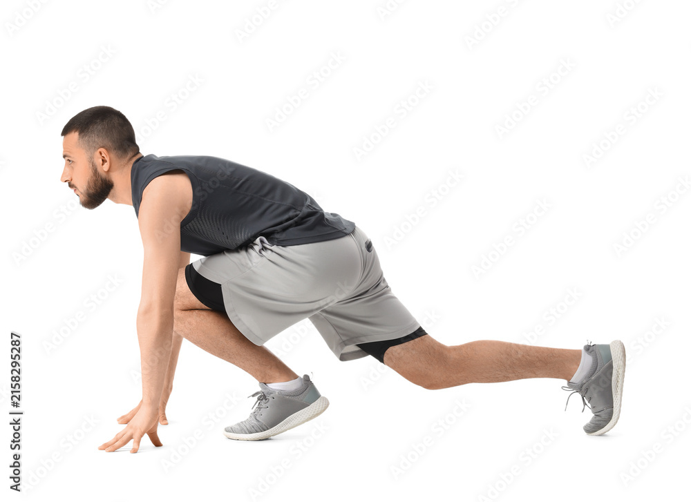 Fototapeta premium Young man in athletic wear in a starting block position, fitness and determination concept, isolated on white background