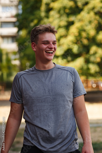 Young basketball player enjoys outdoor practice while smiling in a park during a sunny day, showcasing enthusiasm and passion for the sport with friends nearby