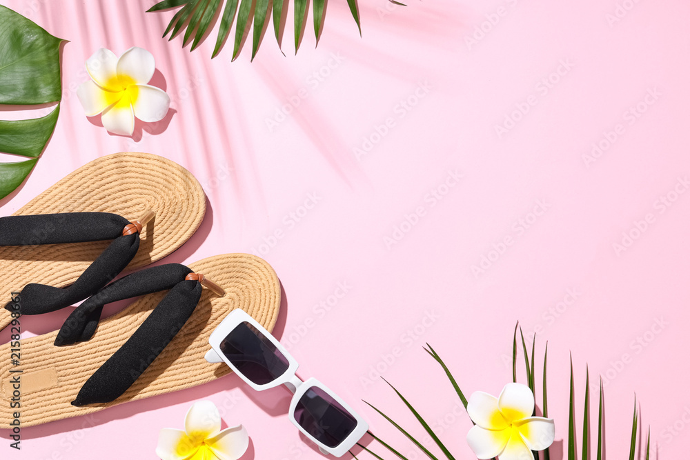 Fototapeta premium Summer composition with beach accessories, plumeria flowers and tropical leaves on pink background