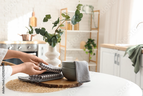 Young woman folding kitchen towels at home, closeup