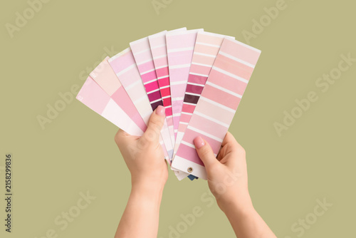 Foto Female hands with pink color palettes on green background