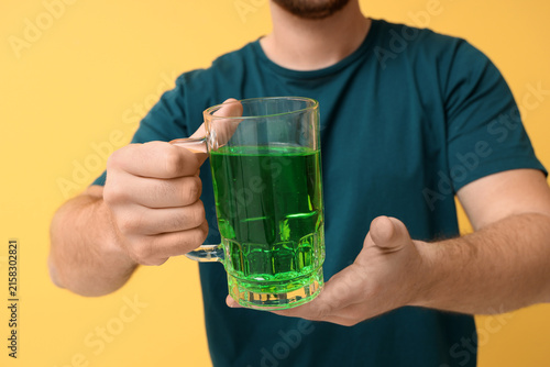 Man with mug of beer on yel...
