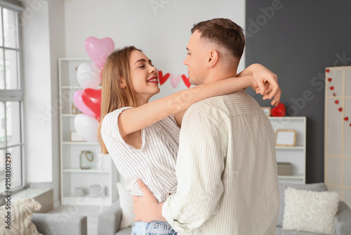 Beautiful young couple celebrating Valentines Day at home and hugging