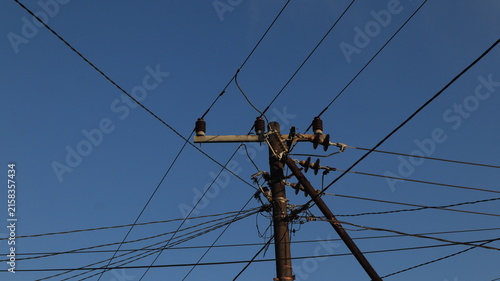 Bild auf Leinwand Network of electric cables on electric poles with a clear blue sky in the aftern