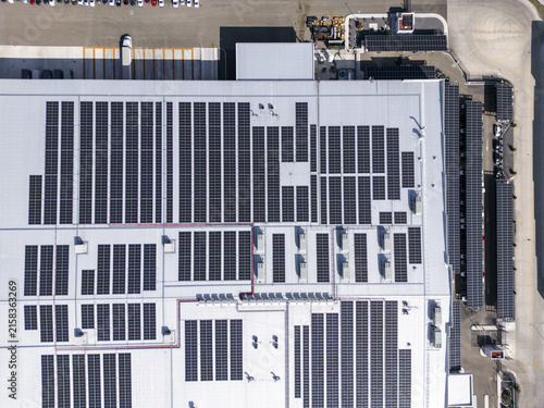 Aerial view of a factory roof covered with extensive solar panels and additional solar arrays in the parking lot in Santiago de Queretaro, Queretaro, Mexico.