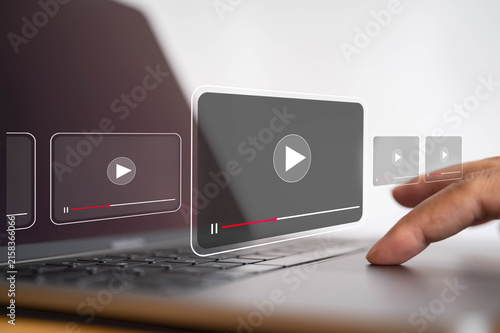 Digital video streaming interface with play buttons over laptop as user interacts with online media, representing video content, multimedia technology, entertainment and online playback.