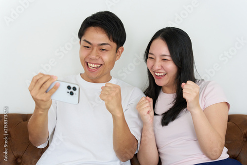 Young Japanese Man and Woman Excitedly Watching Sports on Smartphone Together