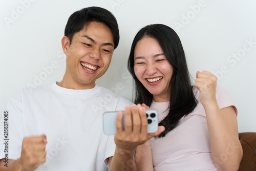 Young Japanese Man and Woman Excitedly Watching Sports on Smartphone Together