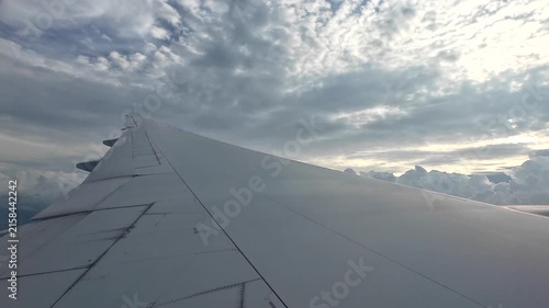 The wing of a large passenger plane floating in the sky during the rainy season.