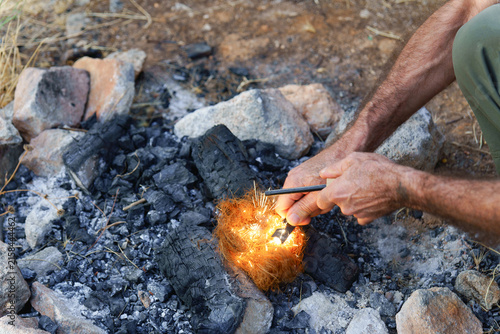 Foto Person using a ferro rod to create sparks, igniting tinder for a survival fire i