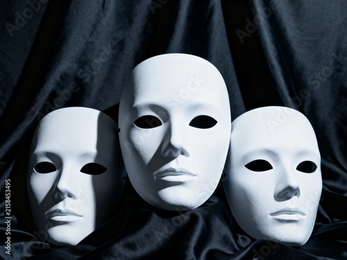 Three White Theater Masks On Black Fabric Backdrop Representing Mystery And Anonymity

