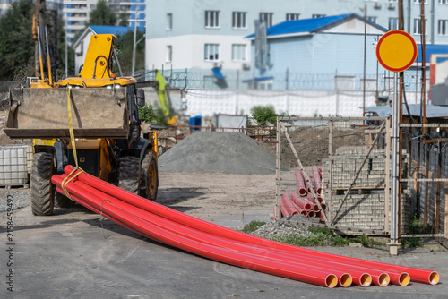 Plastic pipes are transported to the construction site on a summer day