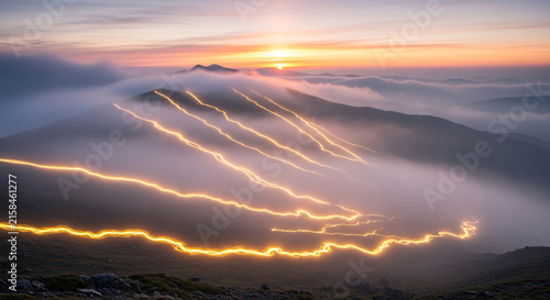 Mountain landscape with glowing ski trails winding down snowy slopes during sunrise above clouds