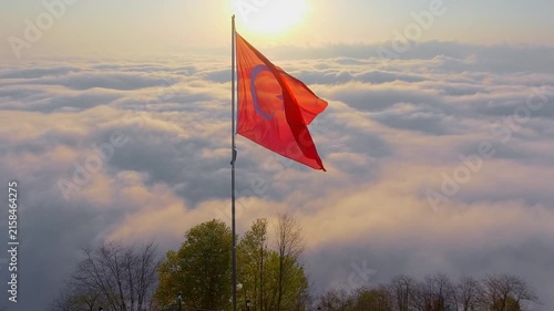 Turkish flag rises above clouds at sunrise with red banner, mountain air patriotic landscape.