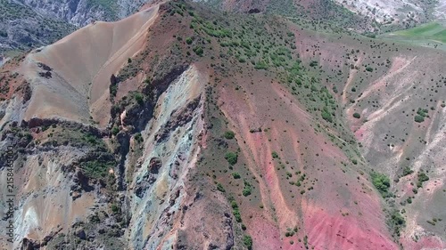 Exposed mineral outcrop reveals red strata and ore bearing layers across a barren slope.
