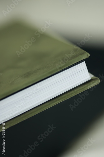 Foto Green velvet hardcover book with white pages on dark table close up, elegant bla