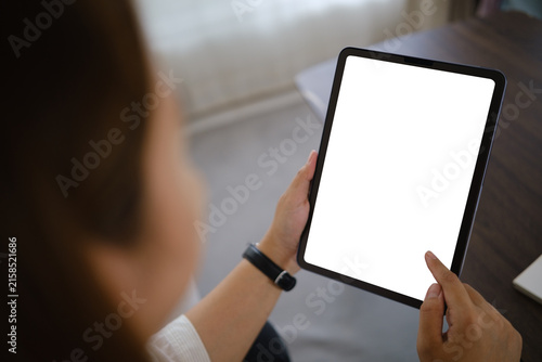 Asian businesswoman holding a tablet with a blank screen for a digital mockup at home.