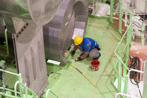 Картината върху платно Shipyard worker engaged in painting and cleaning operations inside a newly built ship, contributing to the final finishing work