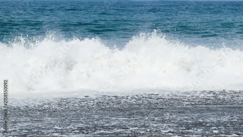Blue sea and large waves and foam. Wave splashing over pebbles at sea. Rolling ocean waves. Summer beach background. Powerful sea waves	