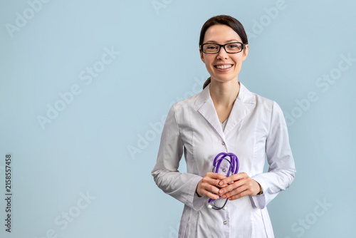 Female doctor holding stethoscope and smiling on blue background