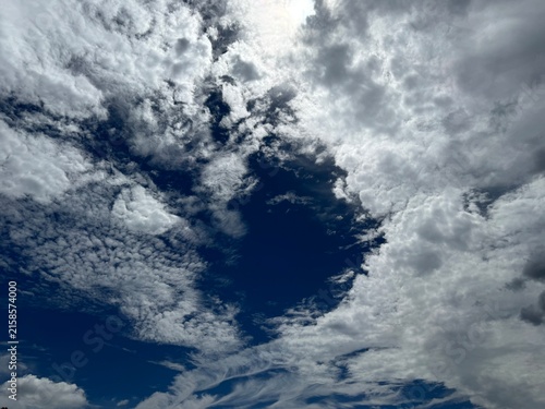 Rippled altocumulus clouds opening to deep blue sky with sunlight