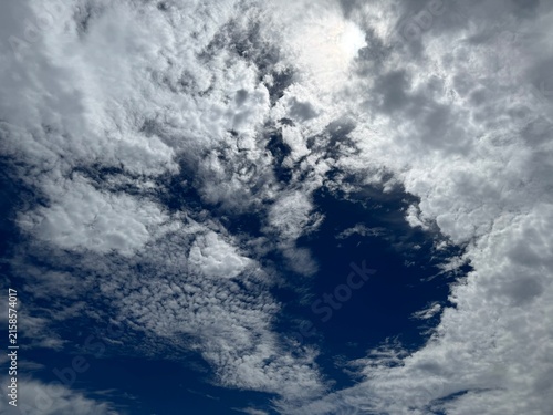 Rippled altocumulus clouds opening to deep blue sky with sunlight