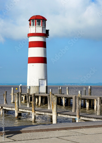 Obraz na płótnie red and white stripped lighthouse on the shore of the sea