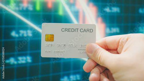 Financial freedom, hands choosing silver credit card for online payment and checkout on stock market screen background.
