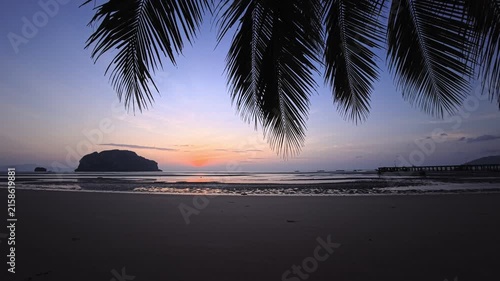Sunset over tropical beach with tidal shoreline, palm trees and turquoise water