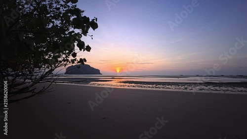 Sunset over tropical white sand beach with tidal flats and silhouetted island