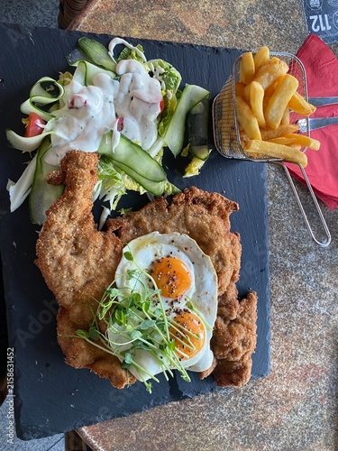 Wiener Schnitzel vom Kalb mit Spiegelei, frischem Salat und knusprigen Pommes frites. Klassisches Restaurantgericht, österreichische Küche, Hausmannskost und authentische Food-Fotografie.