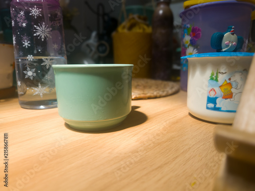 Konstfotografi Mint green ceramic mug on a wooden table in warm sunlight with blurred kitchenwa