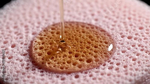 Honey dripping on pink foam surface.
