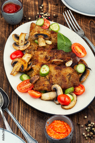 Breaded pork chops fried or schnitzel on rustic wooden table.