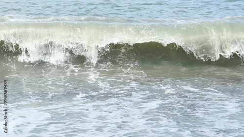 Blue sea and large waves and foam. Wave splashing over pebbles at sea. Rolling ocean waves. Summer beach background. Powerful sea waves	