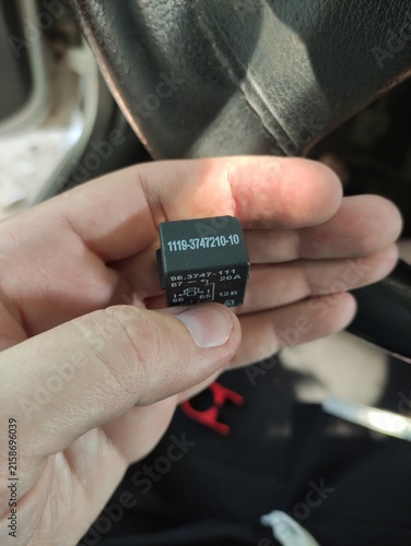 Bild auf Leinwand Hand holding a black car electrical relay showing model number and specification