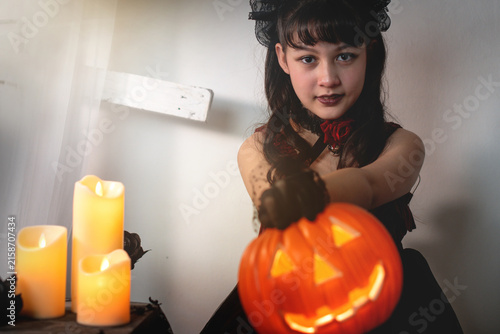 Girl is holding a Halloween pumpkin lantern towards the camera. 