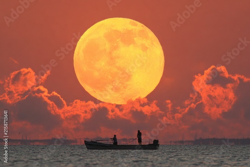 Sunrise/Sunset, large orange moon, silhouettes of two fishermen in small boat