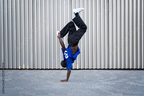 Quadro su tela Male breakdancer performing a handstand on urban street pavement against a strip