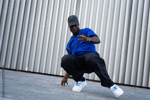 Obraz na plátne Black male breakdancer crouching in urban street style against a metallic wall,